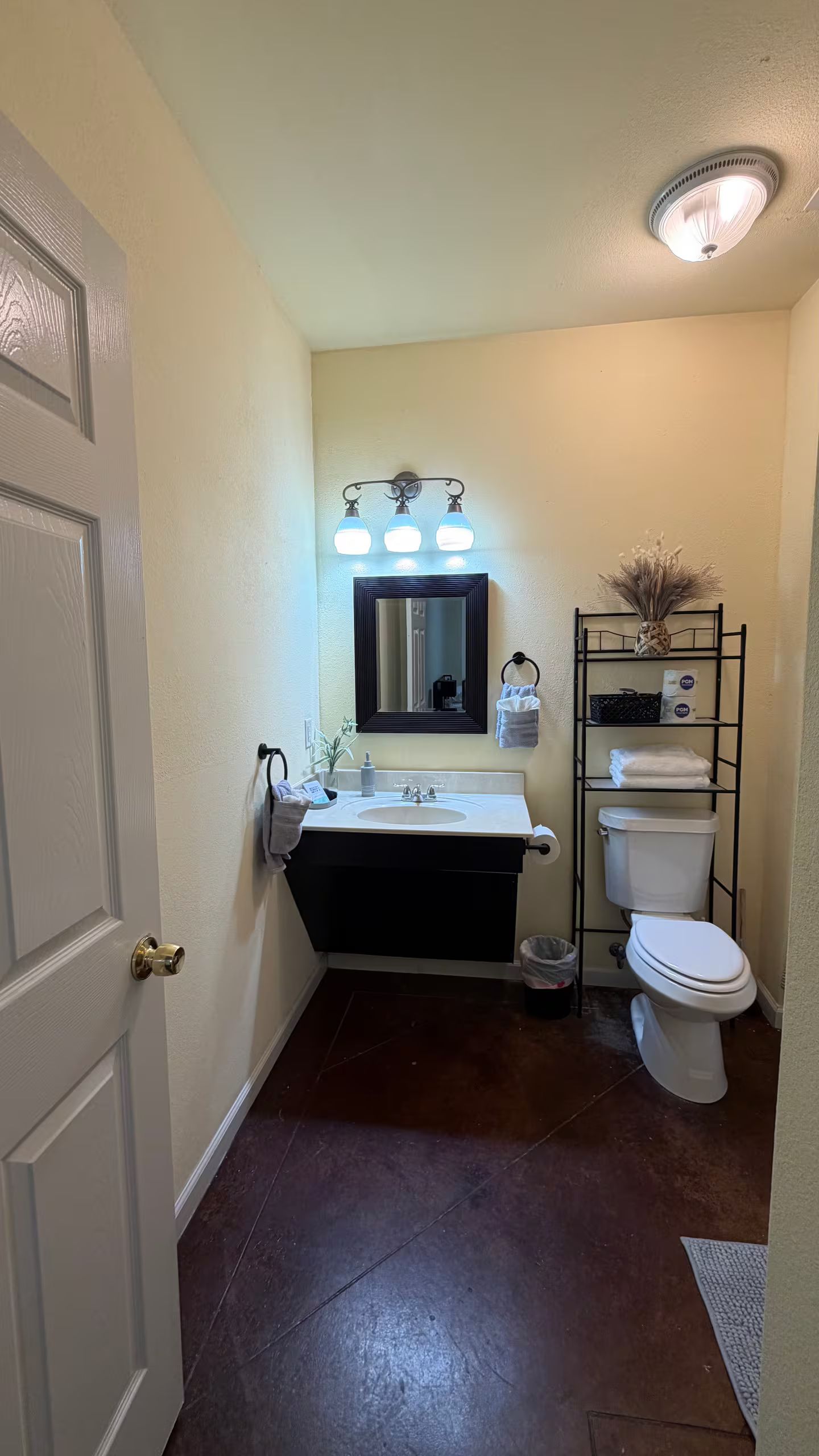 A bathroom with a white sink, dark floor, and a toilet.