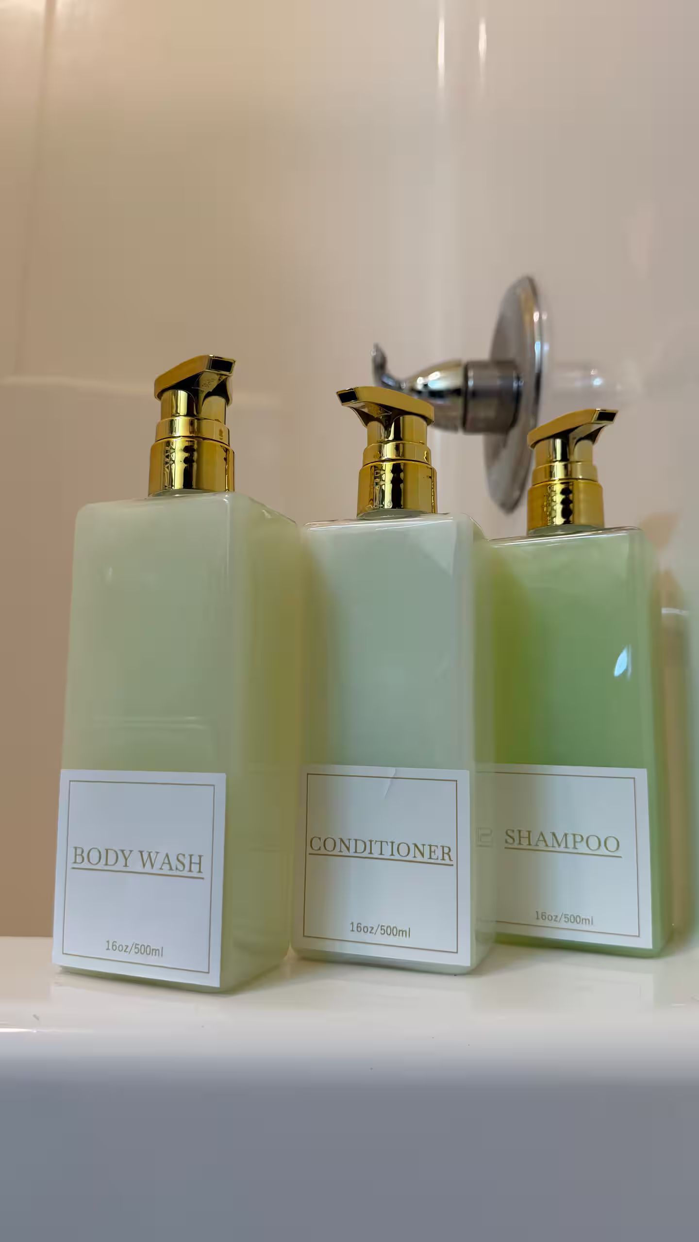 Three bottles of body wash, conditioner, and shampoo on a white shelf.