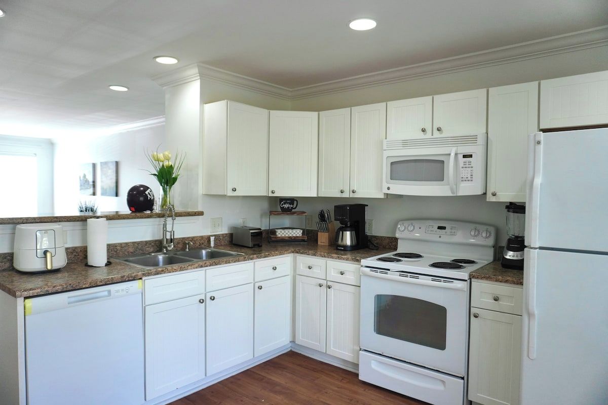 A modern kitchen with white cabinetry, a built-in microwave, a stove, and a dishwasher.