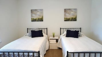 Ein Doppelzimmer mit zwei Betten, einem Nachttisch mit Lampe sowie zwei Landschaftsbildern an der Wand.