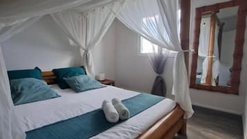 A bedroom with a canopy bed, a wooden headboard, and a large mirror on the wall.