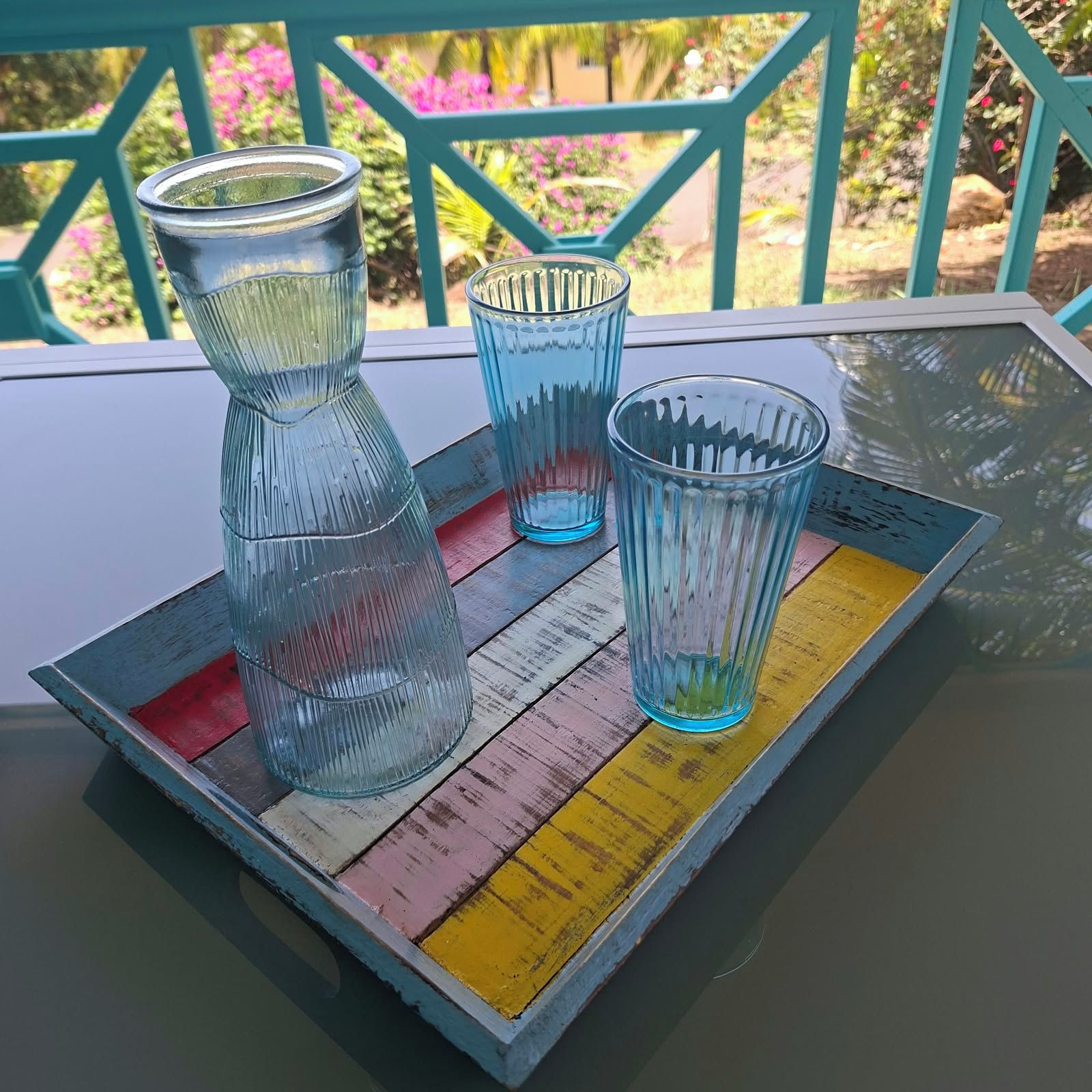 Une table avec trois récipients en verre et un plateau en bois aux couleurs vives.