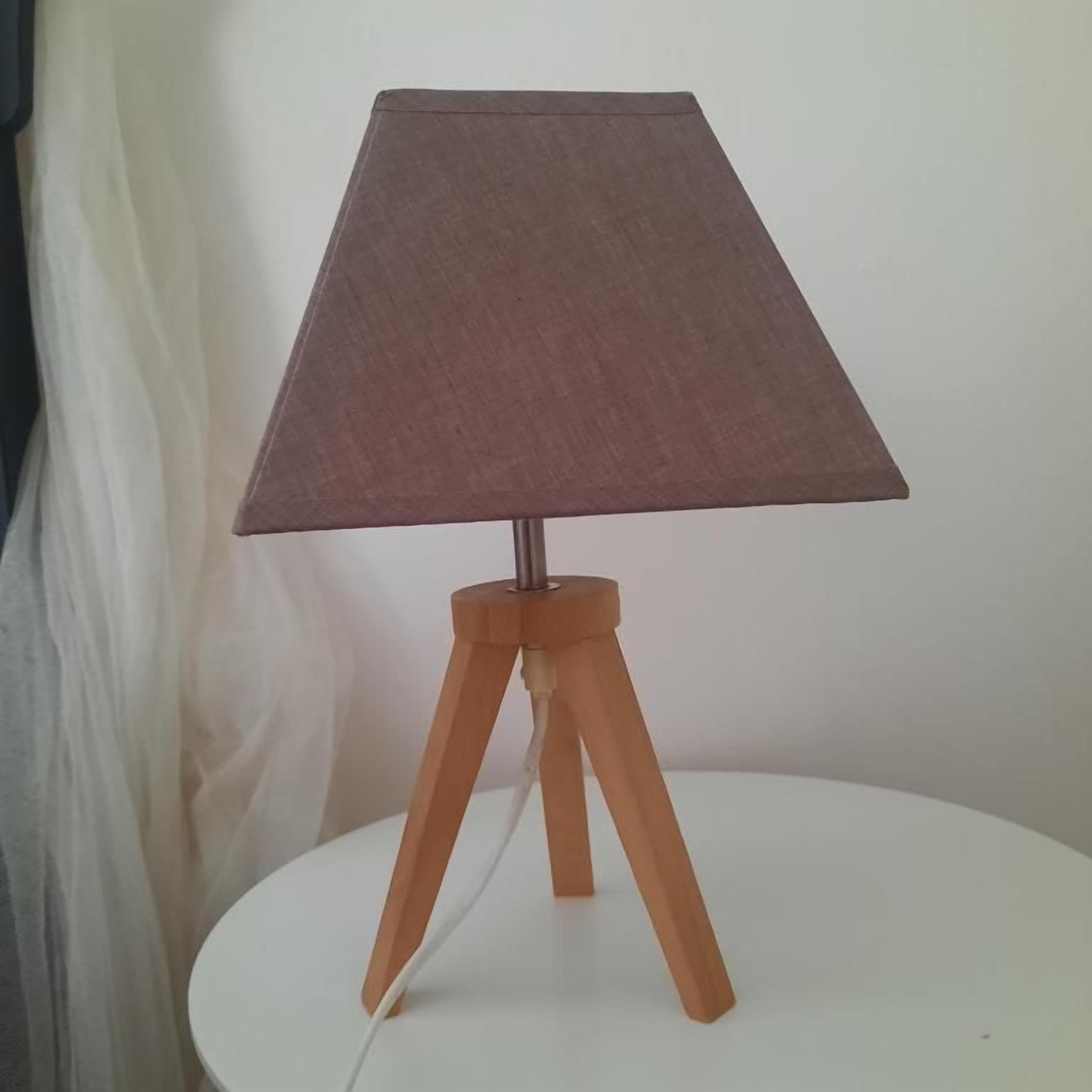 A table lamp with a fabric shade and wooden base on a white table.