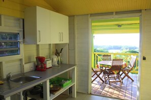 A kitchen with a sink, cabinets, and a coffee maker. There is a balcony with a table and chairs.