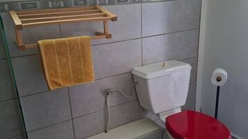 Een badkamer met een toilet, een glazen plank en een handdoekhouder.