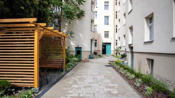 Un sendero estrecho bordeado por edificios con una pérgola de madera y bancos a un lado.