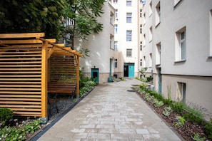 A narrow pathway flanked by buildings with a wooden pergola and benches on one side. - Szmaragd & Grafit 5 min od Starego Rynku (Poznań)