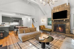 A modern living room with a fireplace, a kitchen in the background, and a dining area. - Ski Pet Friendly 3BR w/ Deck + Resort Access (Sapphire)