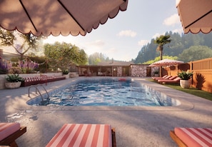 A swimming pool with lounge chairs and umbrellas, surrounded by a landscaped garden and a building with patterned walls. - The Little Bohemian (Occidental)
