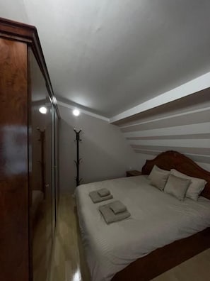 A bedroom with a wooden headboard, a bed with white linens, and a bedside table.