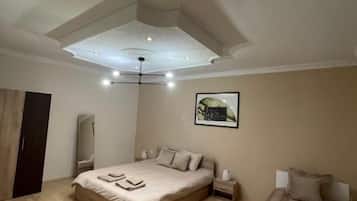 Une chambre à coucher avec un grand lit, des tables de chevet, une armoire et un luminaire au plafond.