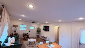 Un salon moderne avec un canapé vert, une table à manger en bois et un ventilateur de plafond.