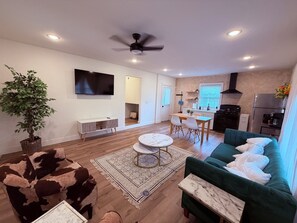 A modern living space with a sofa, a coffee table, a TV, a dining area, and a kitchen. - Tiny homelWalk to DT Rogers lRailyard Bike Park & Live Musicl EV chargers avail. (Rogers)