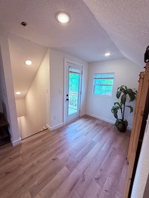 A room with a wooden floor, a white door with a glass panel, and a potted plant. - Tiny homelWalk to DT Rogers lRailyard Bike Park & Live Musicl EV chargers avail. (Rogers)