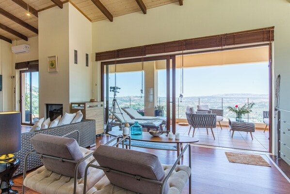 Ein großzügiger Wohnbereich mit Balkon, einer Sofagarnitur, einem Couchtisch und Blick auf die Landschaft.