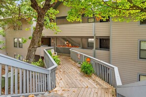 A multi-level building with a wooden deck, outdoor seating, and a tree. - Lake View Condo Near SIlver Dollar City & Table Rock_Outdoor Seating_Free Attraction Tickets (Branson)