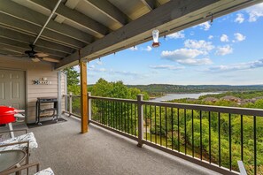 En overdækket balkon med udsigt over en sø og grøn bevoksning.