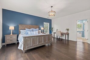 Quarto com uma cama grande, uma escrivaninha e uma cadeira.