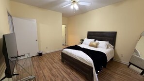 A bedroom with a bed, a ceiling fan, and a door.