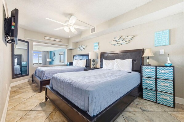 A hotel room with two beds, a ceiling fan, a TV, and decorative wall art. - Direct Oceanfront Balcony with Pools (North Myrtle Beach)