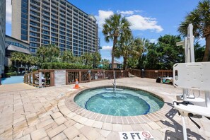 A hot tub surrounded by a pool area with a 3 FT no diving sign, palm trees, and a hotel building in the background. - Direct Oceanfront Balcony with Pools (North Myrtle Beach)