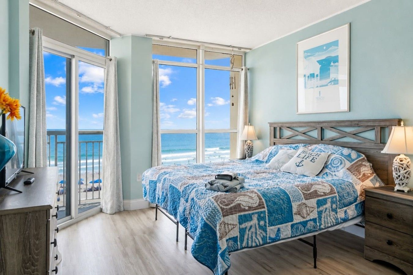 Een slaapkamer met een groot bed, uitzicht op zee en een balkon.