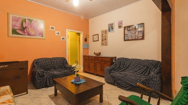 Een woonkamer met twee comfortabele banken, een houten salontafel, een kast en een deur naar een andere kamer.