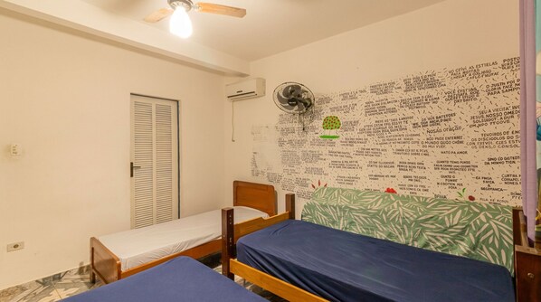 A small, simple room with two single beds, a ceiling fan, and a wall covered with handwritten notes. - House with Pool and BBQ in Rio Escuro (Ubatuba)