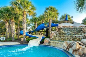 Ein Wasserpark mit einer blauen Rutsche, Palmen und einem Schwimmbecken.