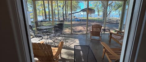 A covered patio with outdoor seating, a ceiling fan, and a view of a park and lake.