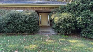A residential house with a front porch, a garage door, and a well-maintained lawn.