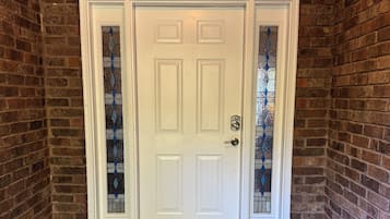 A white door with a glass panel, set in a brick wall with a wooden floor and a concrete floor.