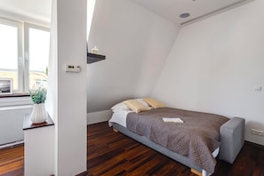 A bedroom with a bed, a bedside table, a potted plant, and a window. - Widok na Ratusz 3 min na Rynek (Poznań)