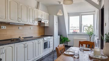 Una cocina moderna con armarios blancos, encimera negra y un comedor con mesa y sillas de madera.