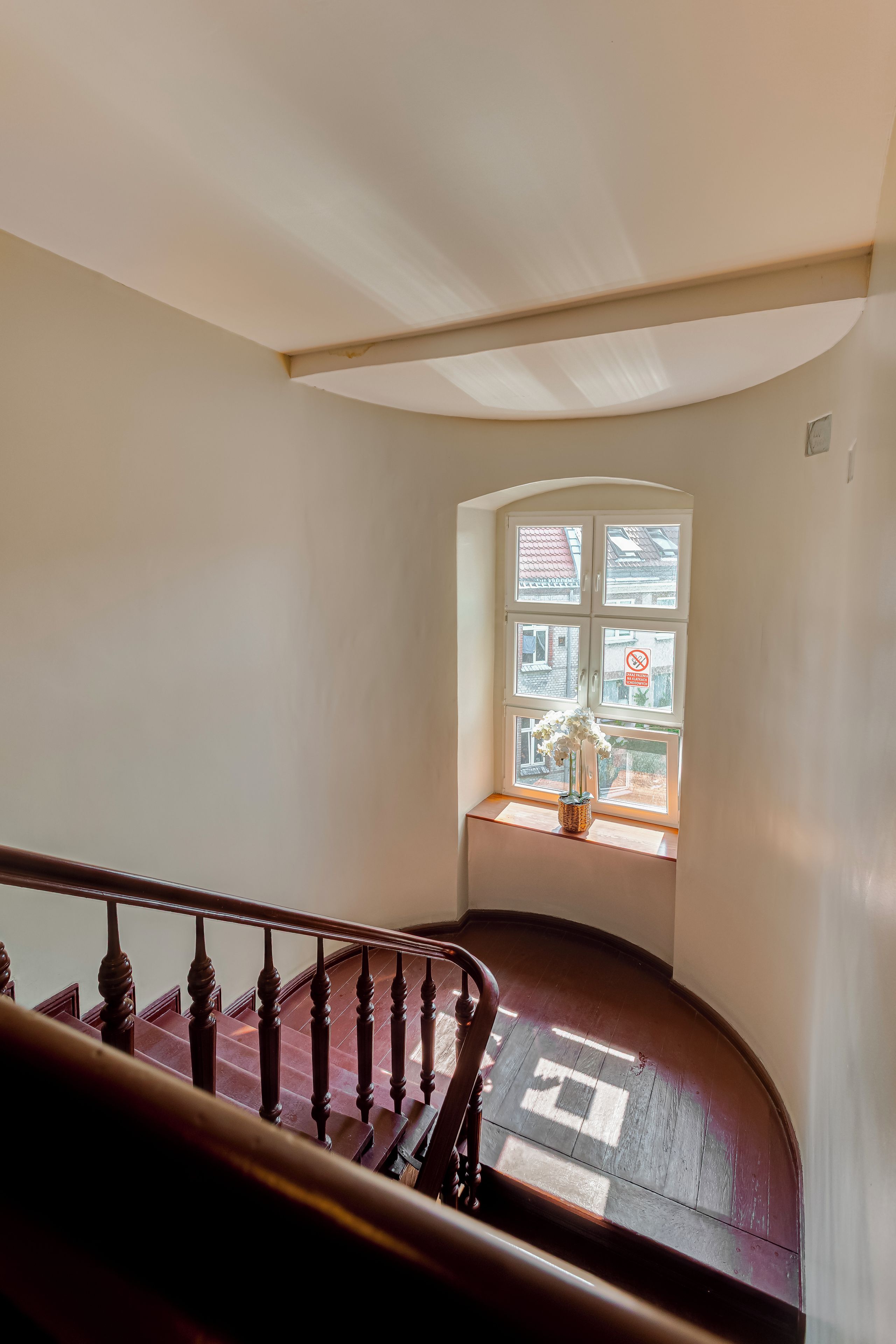 Una escalera con barandilla de madera que conduce a un rellano con una ventana.