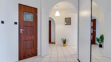 Un pasillo con una puerta de madera, una planta en maceta y un cuadro en la pared.