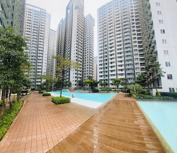 A residential complex with high-rise buildings, a swimming pool, and a well-maintained garden area. - A Cozy 1BR 40sqm in Mandaluyong With City View (Mandaluyong)