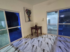 Ein Zimmer mit Fliesenboden, einem Bild an der Wand und einem Fenster mit Blick nach draußen.