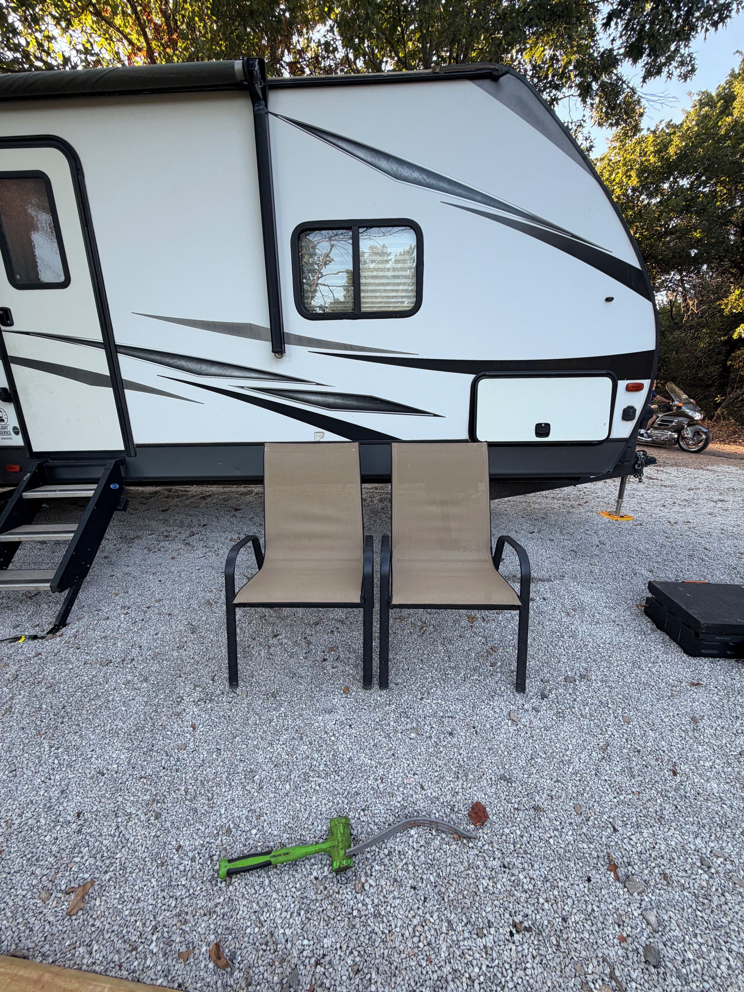 A recreational vehicle with a kitchen area, a table with chairs, and a gravel ground.