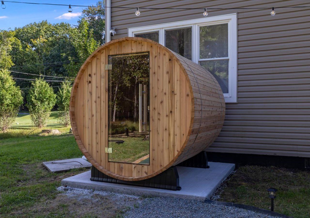 Een houten sauna met een deur, op een betonnen fundering in de open lucht.