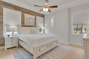 A bedroom with a bed, nightstands, a ceiling fan, and a view of the outdoors. - Recovery Room (Santa Rosa Beach)