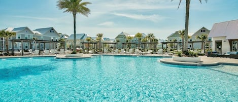 Ein großer Pool mit Liegestühlen und Palmen, umgeben von gebäudekomplexen im Resort-Stil.