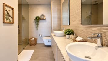 A modern bathroom with a large sink, a toilet, and a shower area.
