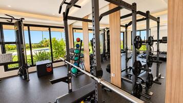 A gym with weightlifting equipment, a bench, and a view of the outdoors.