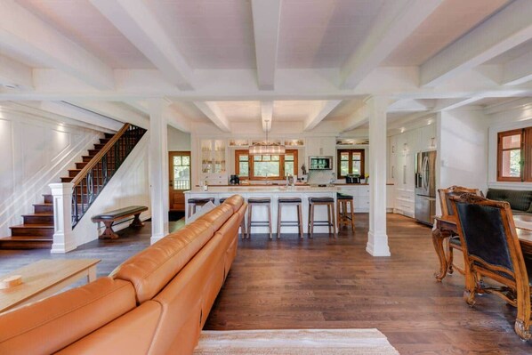 A spacious kitchen with a central island, a dining area with a wooden table and chairs, and a staircase leading to another level.