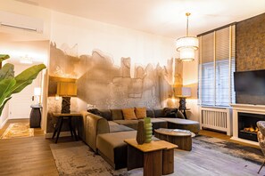 A modern living room with a sectional sofa, a fireplace, and a large wall mural. - Signature Residences - Old Bridge (Heidelberg)