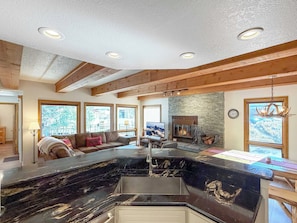 A modern kitchen with a black marble countertop, a built-in sink, and a stone fireplace. - New Listing! Updated Plaza — Walk-to-Lift 3 bedroom Condo with Covered Garage (Crested Butte)