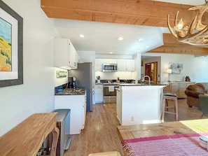 A modern kitchen with white cabinets, a central island, and a microwave. - New Listing! Updated Plaza — Walk-to-Lift 3 bedroom Condo with Covered Garage (Crested Butte)