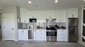 A modern kitchen with white cabinets, stainless steel appliances, and a microwave. - Brand new 1200 sq ft spacious secondary suite, short drive from YYC airport. (Calgary)