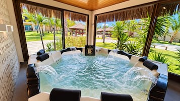Uma banheira de hidromassagem com vista para um jardim tropical e um gazebo.